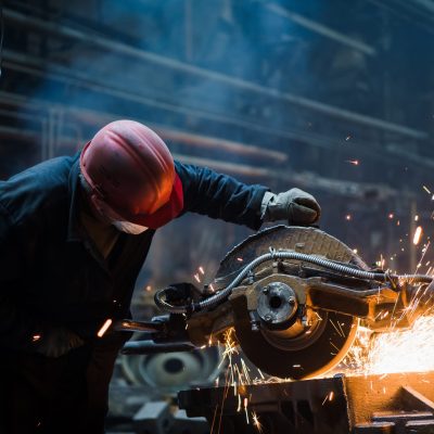 Employee grinding steel with sparks - focus on grinder. Steel factory